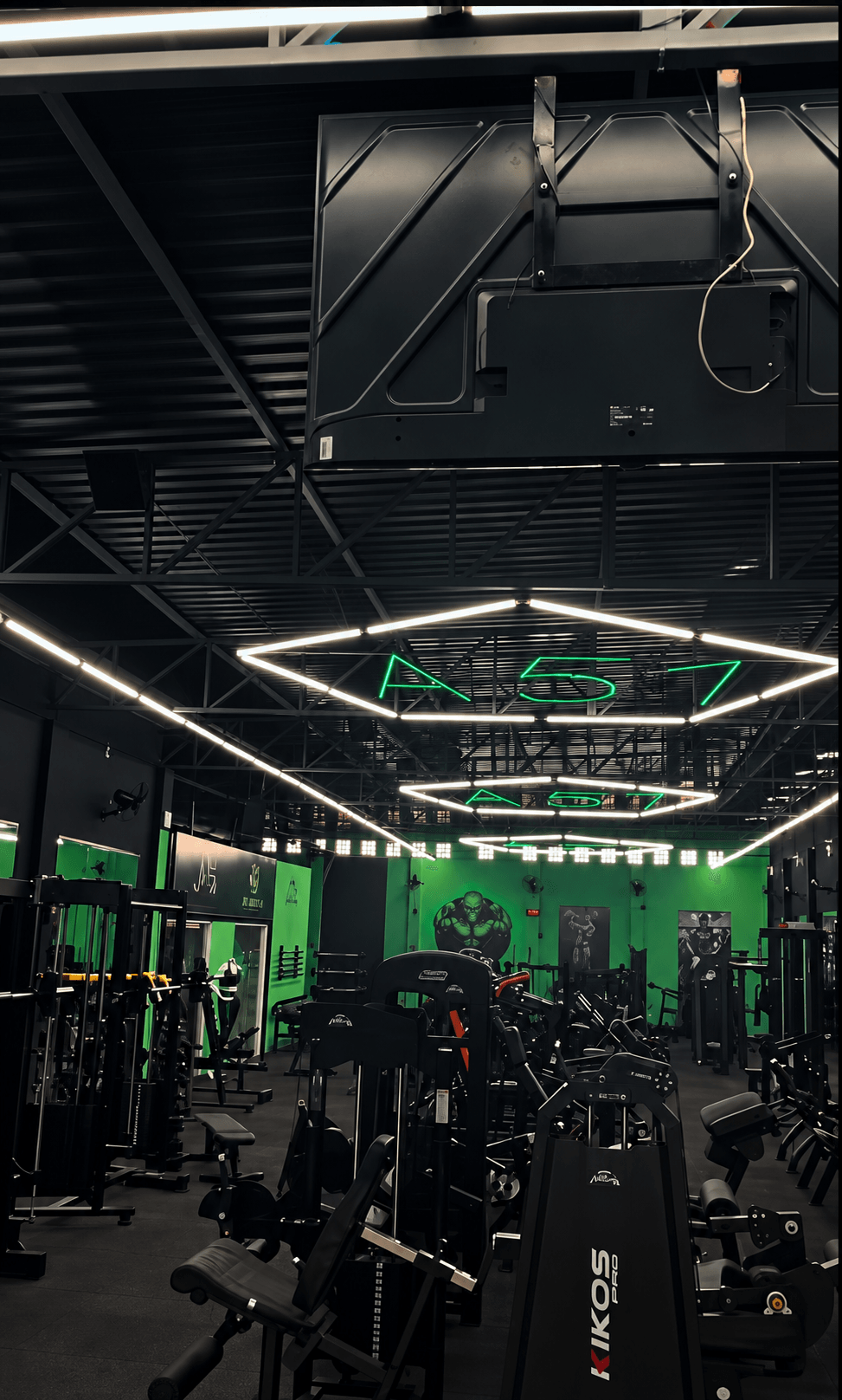 Interior real da Academia Área 51 com equipamentos e iluminação geométrica no teto